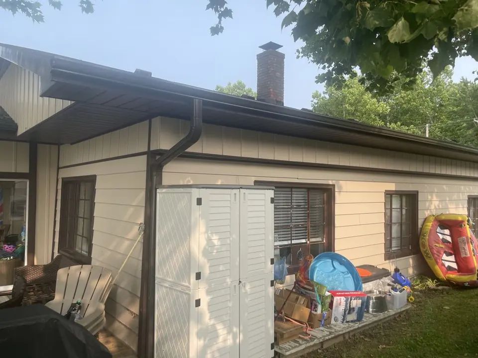 Long brown gutter along a single-story lake house with a corner downspout