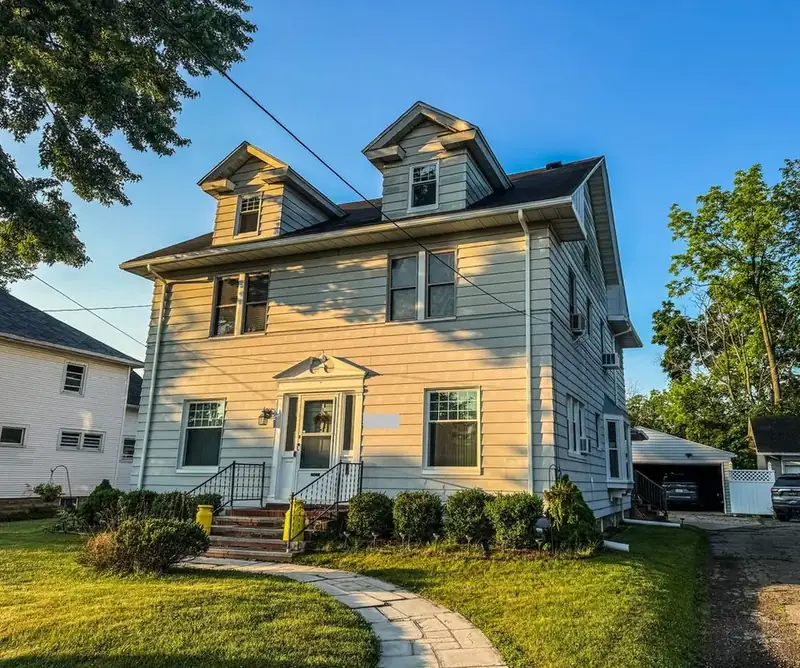 Older 2-story house with dormers, gutters along the eaves and downspouts at the corners